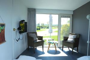 a room with two chairs and a table and a window at Tiny Cottage op Camping "De stal" in Drijber
