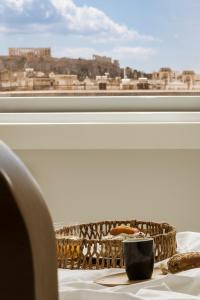Una mesa con una cesta y un plato de comida junto a una ventana. en Elevate Athens, en Atenas