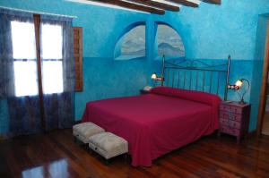 a bedroom with a red bed and blue walls at Casa Rural las Médicas in Buendía