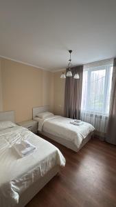 a hotel room with two beds and a window at Asman House in Alamedin