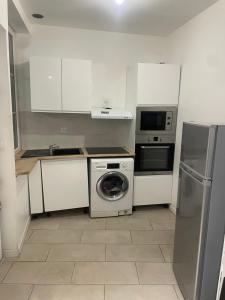 a kitchen with a washing machine and a microwave at Appartement meublé in Alès