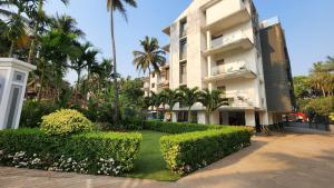un edificio con árboles y arbustos delante de él en Luxury 3bhk penthouse Candolim beach 10 mins, en Goa