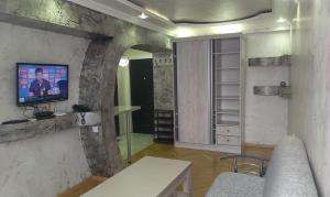 a living room with a tv on a stone wall at Irakli's Apartment with Sea view in Batumi