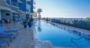 a swimming pool next to a building and the ocean at Romantic Beachfront Sunsets in Panama City Beach
