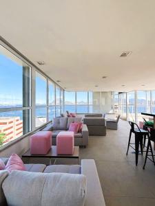 uma sala de estar com sofás, mesas e janelas em Unihome Studio em Niterói