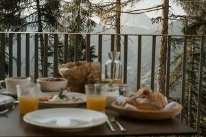 ein Tisch mit Tellern voller Essen und Gläsern mit Orangensaft in der Unterkunft Chalet Herol in Lüsen