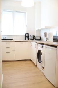 a kitchen with white cabinets and a washer and dryer at Wunderschönes Single Apartment in Berlin