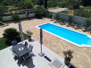 una piscina con sillas, una mesa y sombrillas en Island Hvar Villa LeChalet with Pool, en Bogomolje