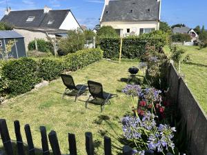Un patio con dos sillas y algunas flores. en 767 - Maison dans un lieu calme à 850m de la plage, en Erquy
