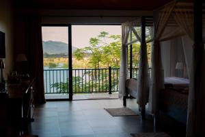 a bedroom with a balcony with a view of the water at Waters Edge Liwonde in Liwonde
