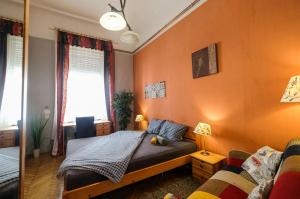 a bedroom with orange walls and a bed and a couch at Pesto private rooms in Budapest