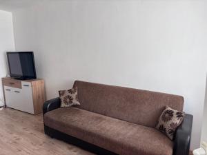 a brown couch in a living room with a tv at The Knight's Rest in Hunedoara