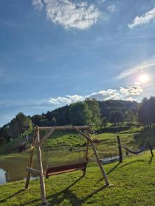 a wooden fence in the grass next to a lake at Domki pod Bukowym Lasem in Wańkowa