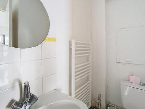 Un baño blanco con lavabo y espejo. en Le Wellington, en Arras