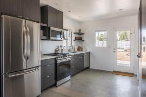 a kitchen with a stainless steel refrigerator and gray cabinets at Skull Rock Cottage - Walk to Town & Hot Tub, Star Gazing home in Joshua Tree