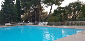 a large blue swimming pool with white chairs and trees at Chambre d'hôtes vue imprenable mer in Nice +11 photos
