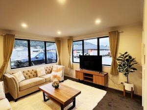 a living room with a couch and a flat screen tv at 7th Heaven in Rotorua in Rotorua