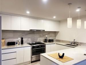 a kitchen with white cabinets and a stove top oven at 7th Heaven in Rotorua in Rotorua +9 photos