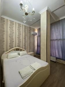 une chambre avec un lit blanc et un lustre dans l'établissement Hotel AISI, à Koutaïssi