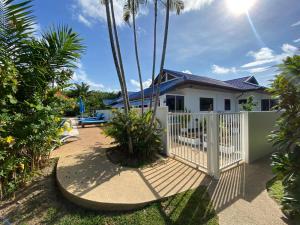 ein Haus mit einem weißen Zaun und Palmen in der Unterkunft Villa Jasmine in Rawai Beach