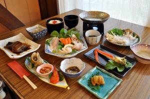 a wooden table with plates of food on it at Pension Arumeria in Wakkanai