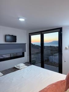 a bedroom with a bed and a large window at Komos view in Pitsidia