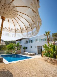 an umbrella over a swimming pool in front of a house at Blue Hill House Ibiza 360-degree Exclusiveness in San Jose