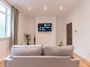 a couch in a living room with a tv on the wall at Elegant St Margarets 1BR near Transport London Pass the Keys in Twickenham