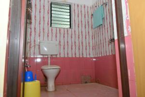 a bathroom with a toilet and a pink wall at Puri studio apartment in Puri