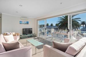 a living room with white furniture and a large window at Crow's Nest Apartments in Whitianga