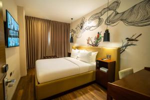 a hotel room with a bed and a television at The Henry Hotel Roost Bacolod in Bacolod