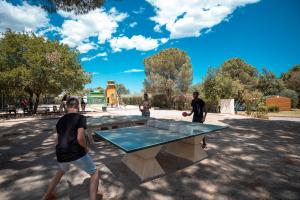 Camping des Alberes في Laroque-des-Albères: مجموعة من الناس تقف حول طاولة بينج بونغ
