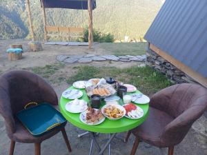 ein grüner Tisch mit Essen darauf und zwei Stühlen in der Unterkunft Mariiko's cottages in Iprari