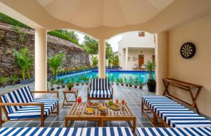 a patio with chairs and tables and a pool at Villa Sol- A Hilltop Villa in Udaipur in Jāmb