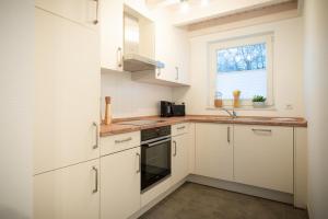 a kitchen with white cabinets and a window at VechteSonne - Nordhorn in Nordhorn