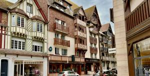 a group of buildings on a city street with cars at Le Trophée Boutique Hôtel Spa- La Loggia Appart'hôtel in Deauville