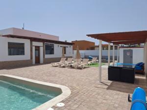 Un patio con piscina y sillas y una casa. en Villa Experience Heated Salty Water Pool, en Caleta de Fuste