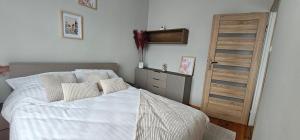 - une chambre avec un lit blanc et une porte en bois dans l'établissement Apartament 2 pokojowy z widokiem na morze, à Sarbinowo 6 autres photos