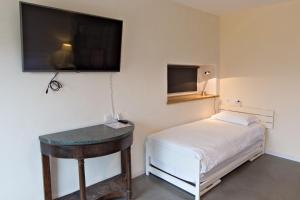 a small bedroom with a bed and a flat screen tv at Le Faing Du Bray in Plombières-les-Bains