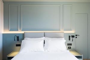 Un dormitorio con una cama con almohadas blancas. en Bfor Hotel, en Nola