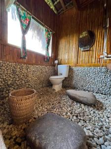a bathroom with a toilet and a rock floor at Bình Minh homestay in Hoàng Su Phì