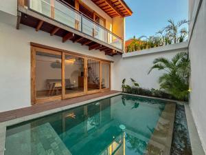 a house with a swimming pool in front of a house at Campbar 2 by AGATA in Canggu