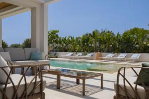 a patio with a pool and chairs and a table at Villa Mareiva - Heated Pool, Beach 150 mt in Pozzallo