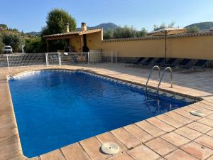 a pool with blue water in front of a house at Aldora Rural Casa con piscina in Moratalla