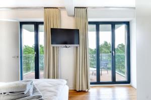 ein Schlafzimmer mit einem TV an einer Wand mit Fenstern in der Unterkunft Ferienwohnung Strandloft 12 im Haus Düne 7 Prora in Binz