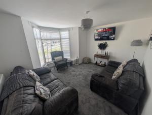 a living room with a leather couch and a chair at Stadium View 5-Bed Retreat + Parking in Swansea