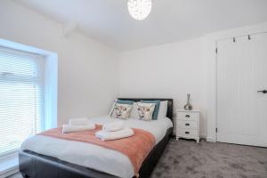a bedroom with a bed with two towels on it at Stadium View 5-Bed Retreat + Parking in Swansea
