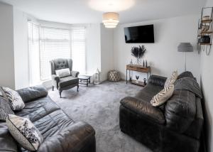 a living room with a leather couch and a chair at Stadium View 5-Bed Retreat + Parking in Swansea