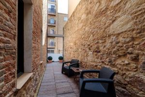un patio con sillas, una mesa y una pared de ladrillo en Alojamiento Singular, en Zamora