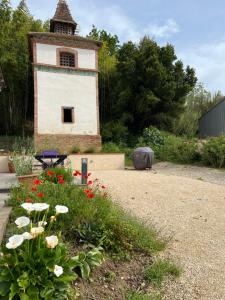 ein Gebäude mit einem Turm in einem Garten mit Blumen in der Unterkunft Maison Villa Santina in Piquecos + 5 Fotos